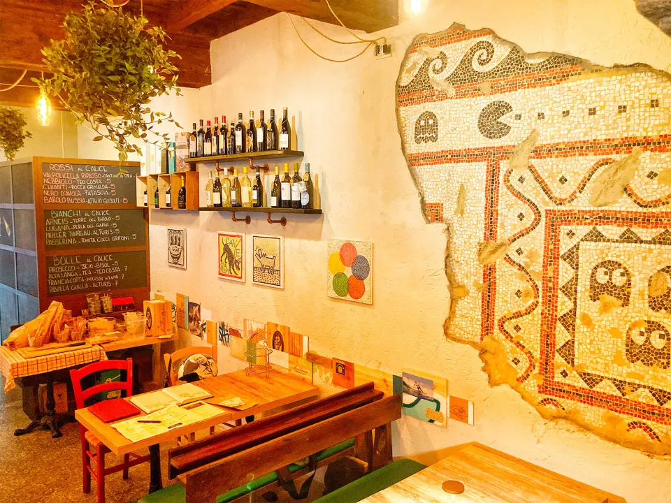 La sala del Sancarlino con il mosaico, la lavagna dei vini al calice e le bottiglie sugli scaffali